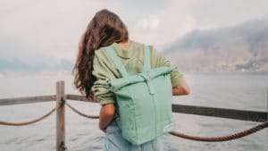 A woman is standing on a dock with a green backpack.