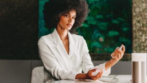 Eine Frau mit Afro-Haaren sitzt an einem Tisch.