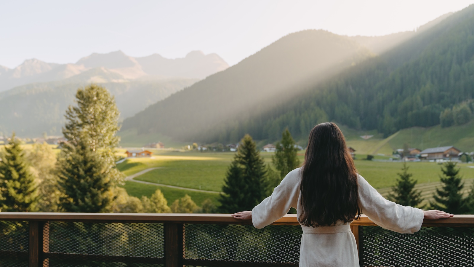 Eine Frau im Gewand blickt auf ein Tal im Hotel Quelle in Südtirol.